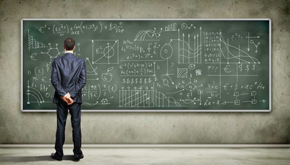 Business person standing against the blackboard with a lot of data written on it